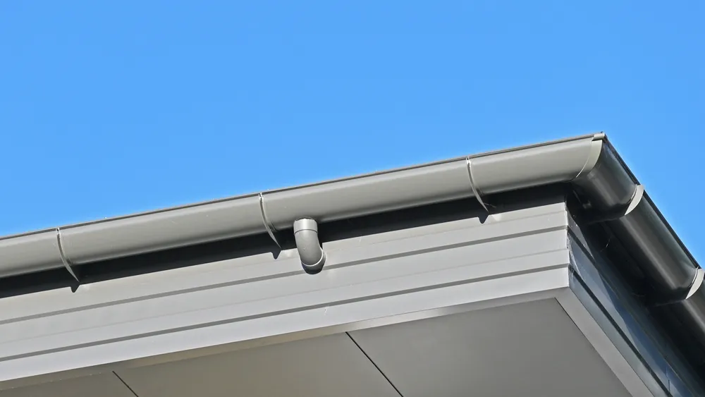 Half round metal roof gutter with an internal downpipe